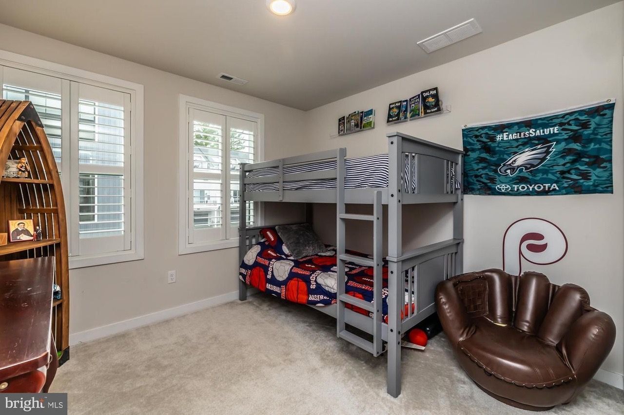 Bedroom with bunk beds, an Eagles flag, and a baseball glove chair.