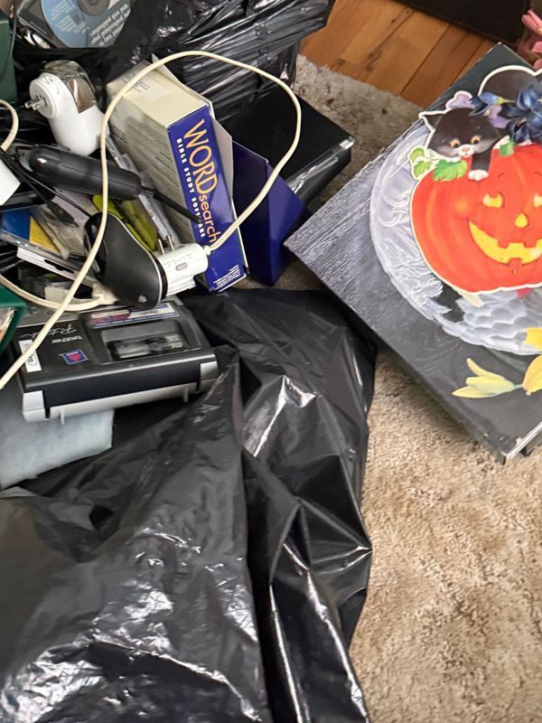 Black trash bags overflowing with electronics and Halloween decor.