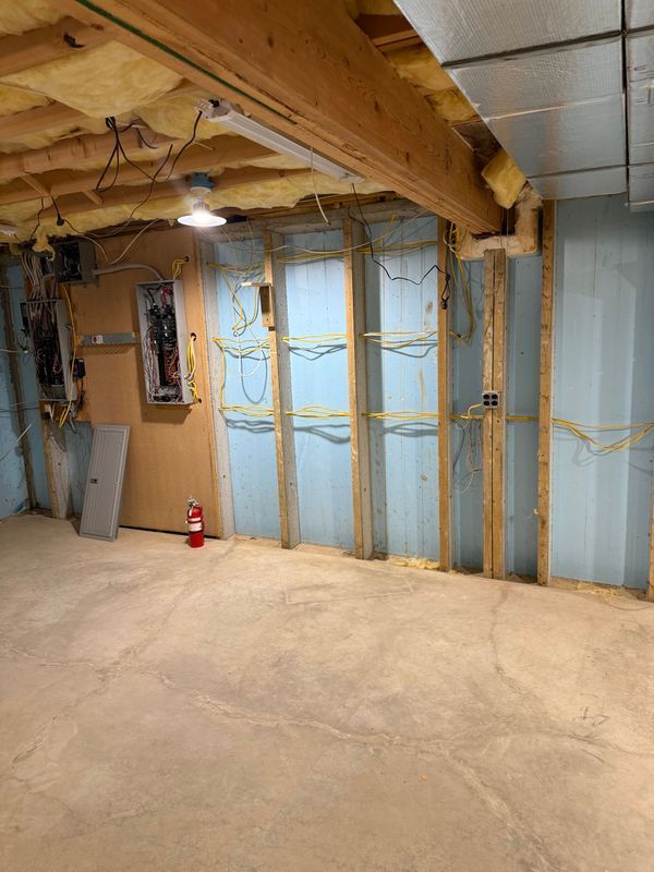 Basement with exposed framing, insulation, electrical wiring, and a fire extinguisher.