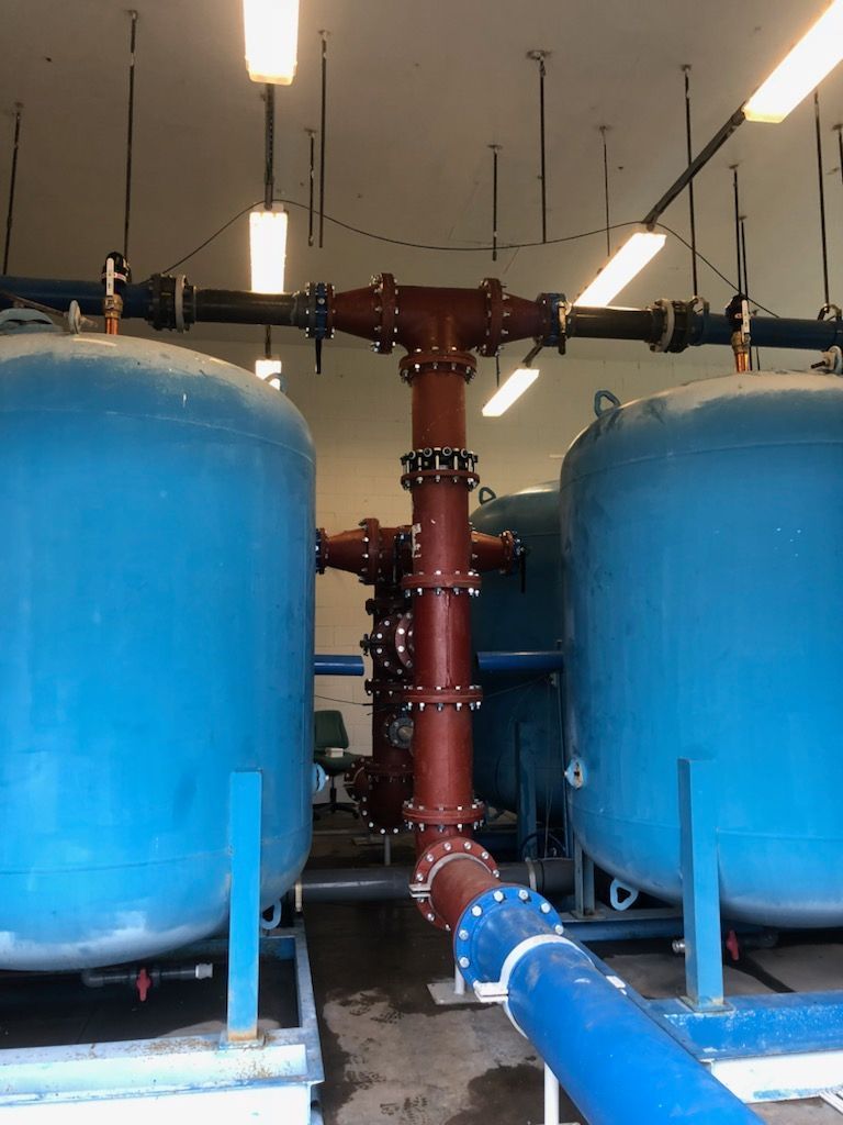Two blue tanks with connected red and black pipes in a utility room.