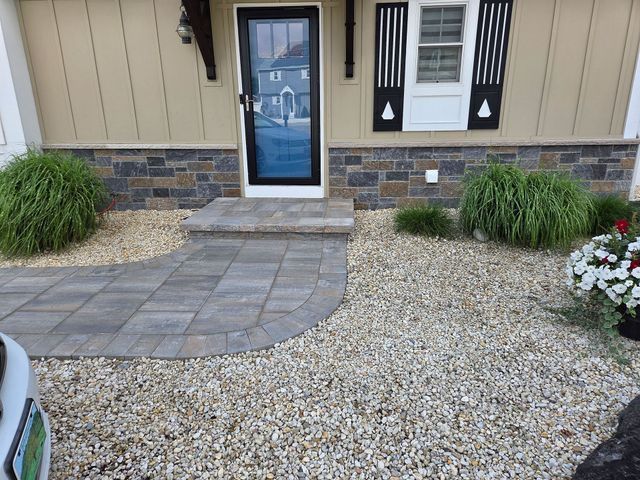 Front walkway with paver path, gravel yard, and a tan house entry with a blue door.