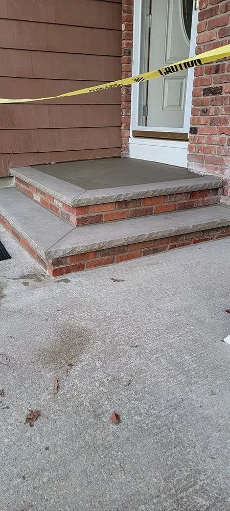 Front porch steps taped off with yellow caution tape in front of a brick house entrance