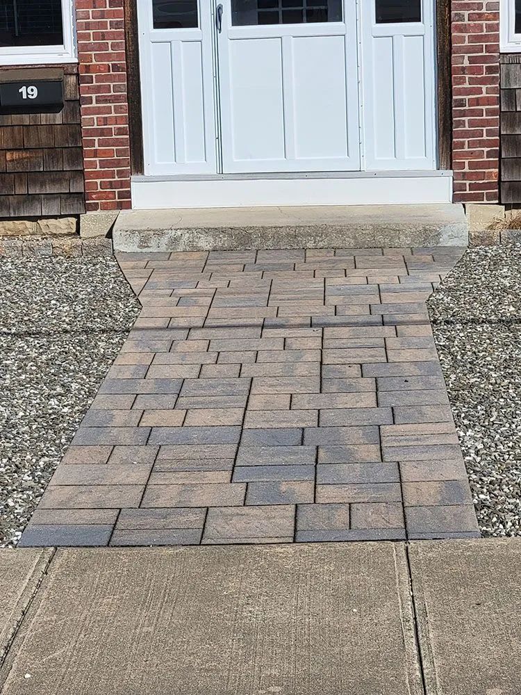 Brick paver walkway leading to a white front door on a house entrance