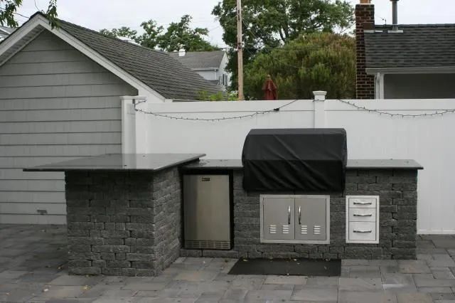 Stone memorial wall with plaques and a black awning in a residential setting