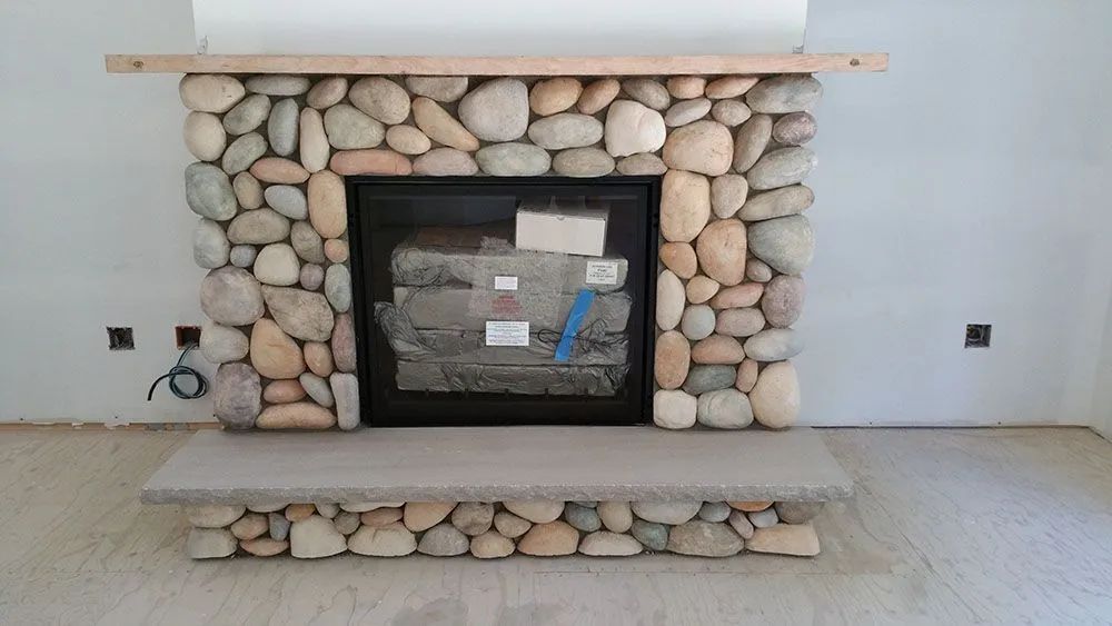 Stone fireplace with a wooden mantel and hearth in a white room