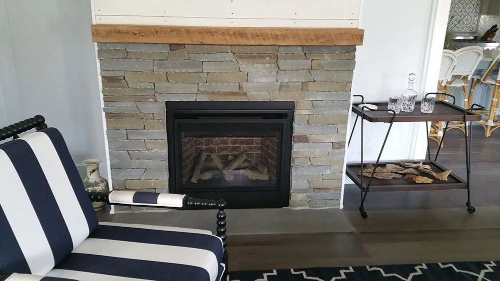 Living room fireplace with stone surround, striped chair, and small side table