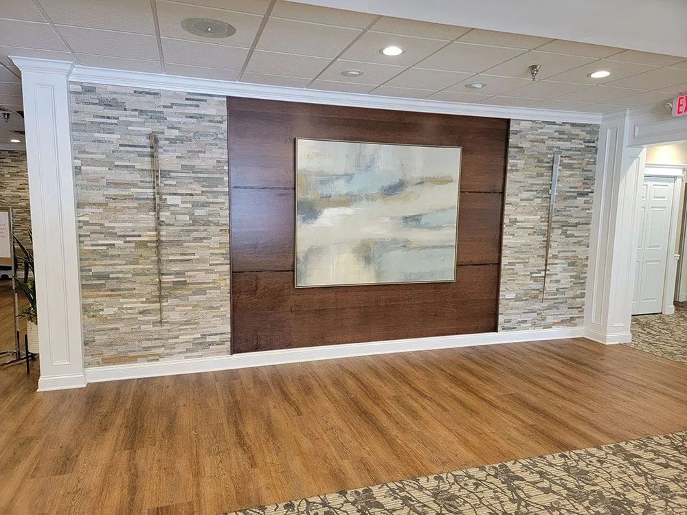 Empty lobby with wood floor, stone accent wall, and large abstract painting centered on a wooden panel