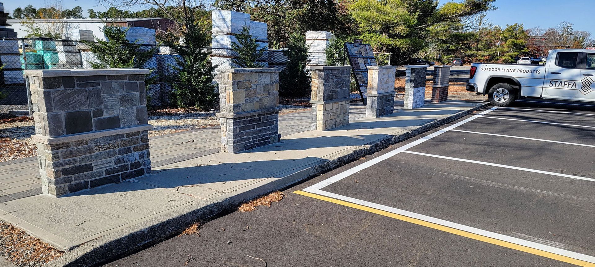 Stone memorial wall and pillars along a parking lot with a white truck in the background