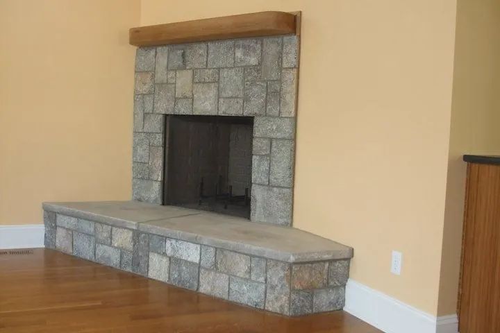Stone fireplace with a raised hearth in a hardwood-floor living room