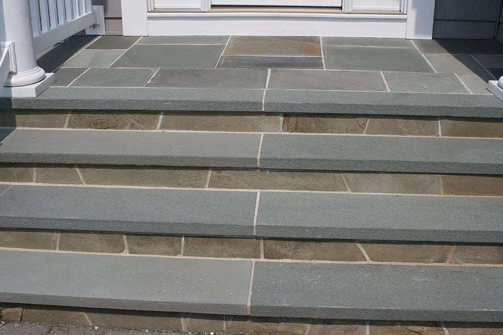 Gray stone steps leading to a white building entrance with a tiled landing
