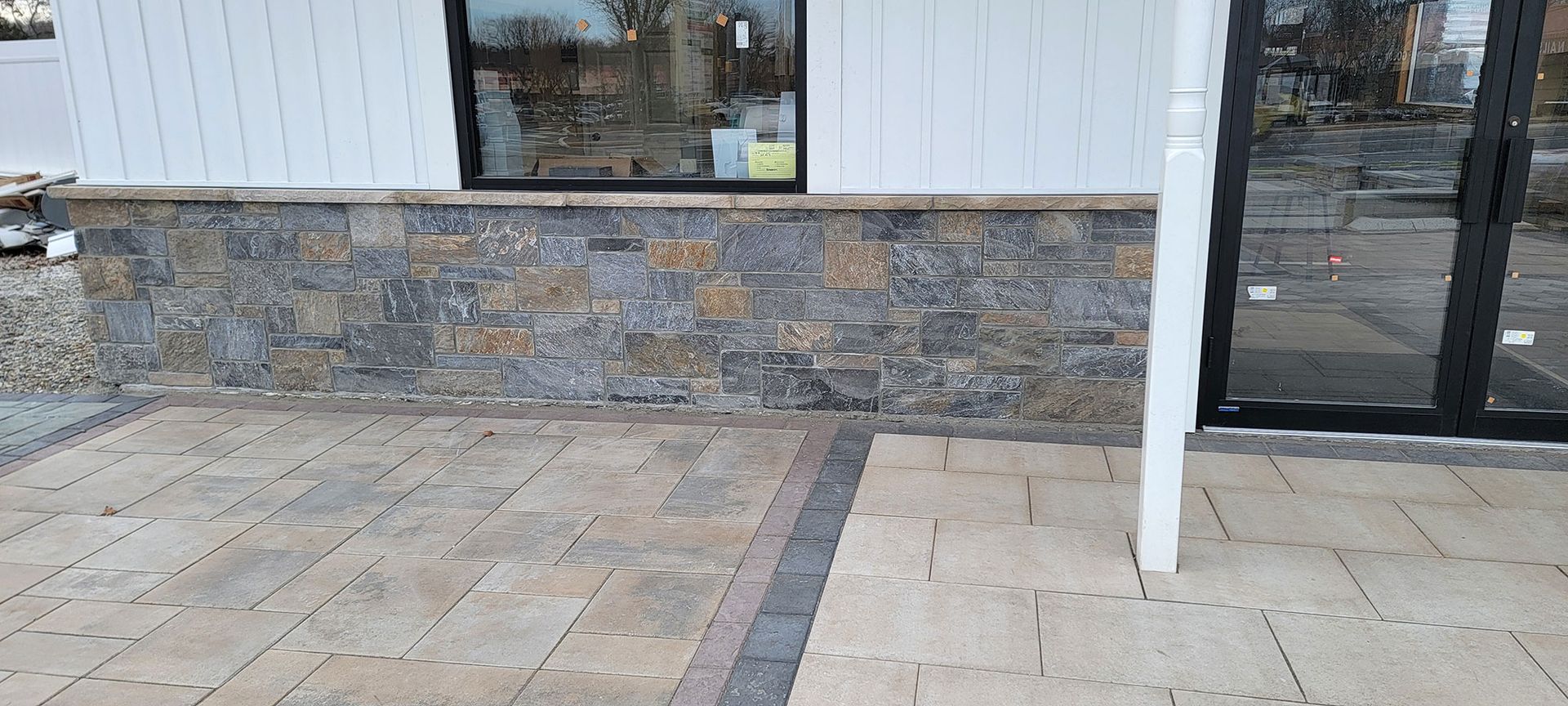 Stone-faced storefront with tiled sidewalk and glass entrance.