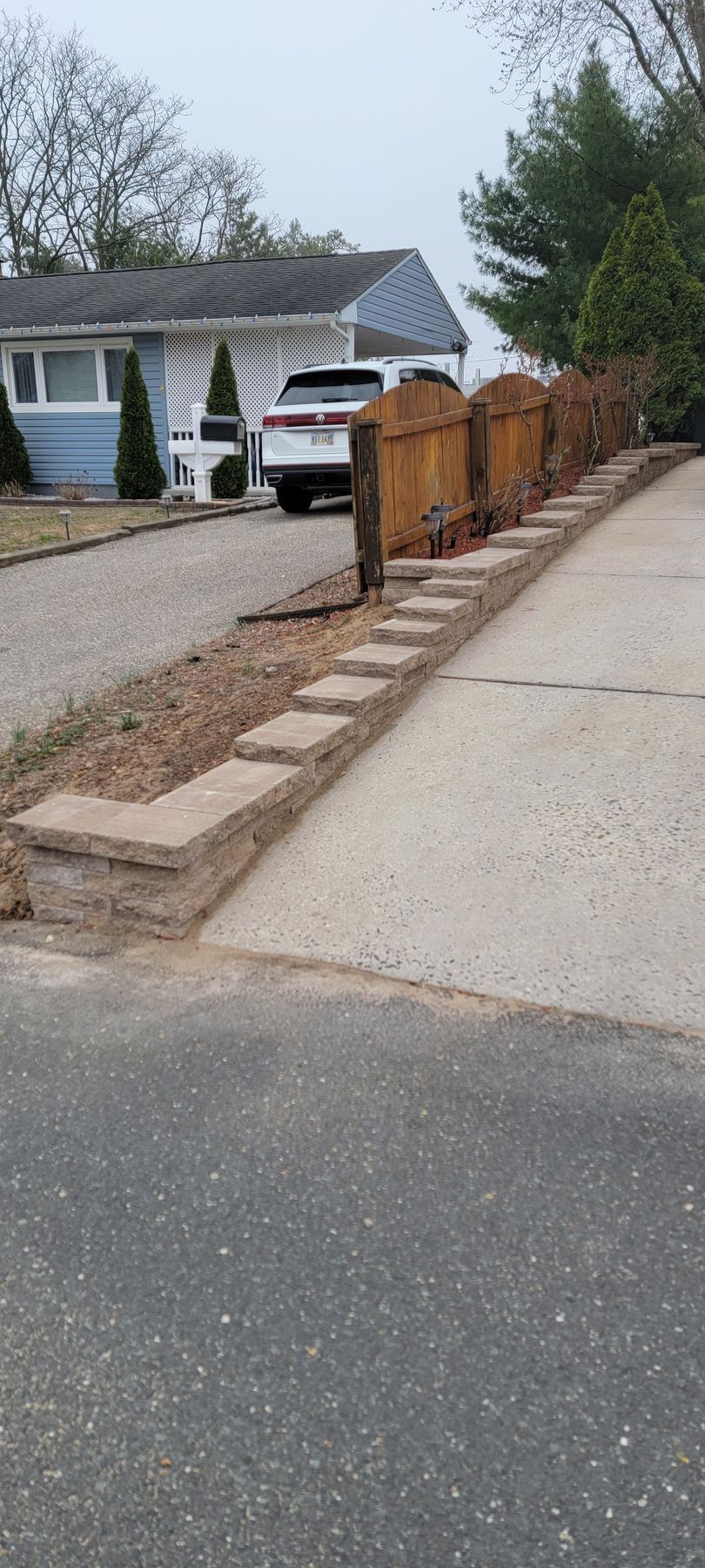 Brick mailbox wall beside a driveway with a white van and house in the background