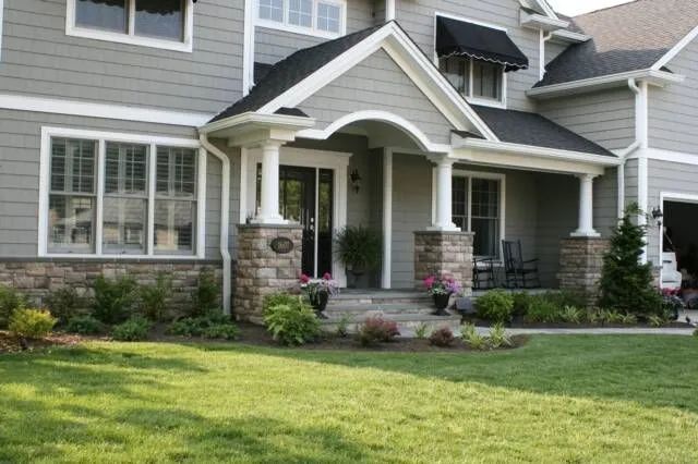 Suburban house with gray siding, white trim, stone porch columns, and a green lawn