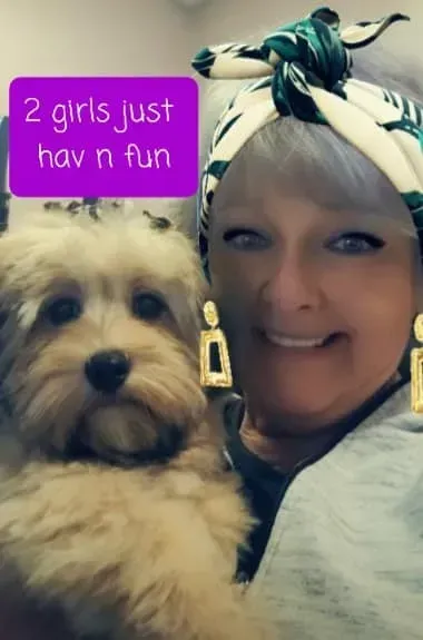 Woman smiling with a small fluffy dog; purple text says “2 girls just hav n fun”
