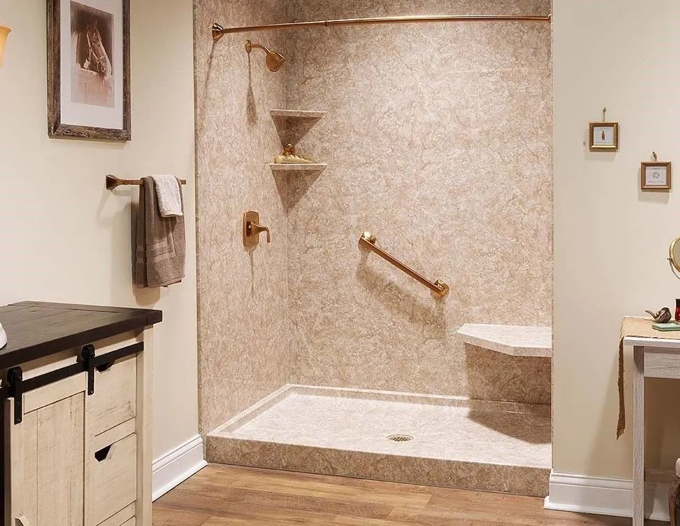 A barrier-free walk-in shower with a built-in seat, grab bar, and bronze fixtures, featuring a neutral stone-look interior.