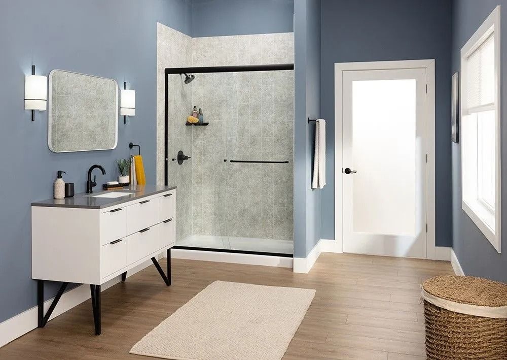 Modern bathroom with blue walls, a white vanity, a tiled shower, a white door, and light wood flooring.