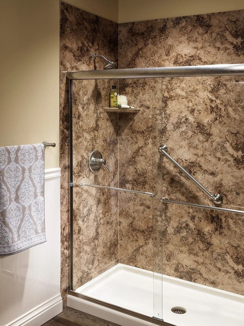 A walk-in shower with brown granite-pattern walls, a glass sliding door, and a safety grab bar inside.