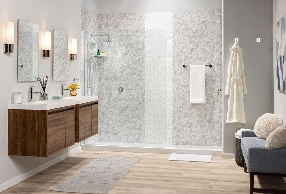A modern bathroom features a double floating wood vanity, marble shower walls with a mosaic accent, and a blue bench.