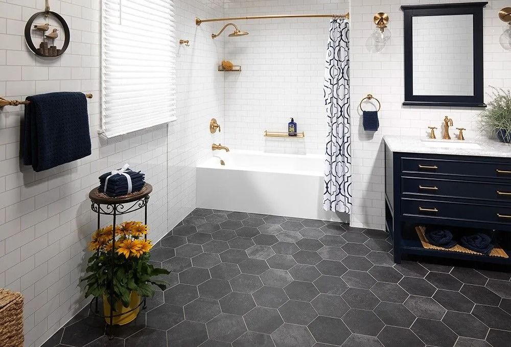 A bathroom with white subway tile walls, a navy blue vanity, and dark gray hexagonal floor tiles.