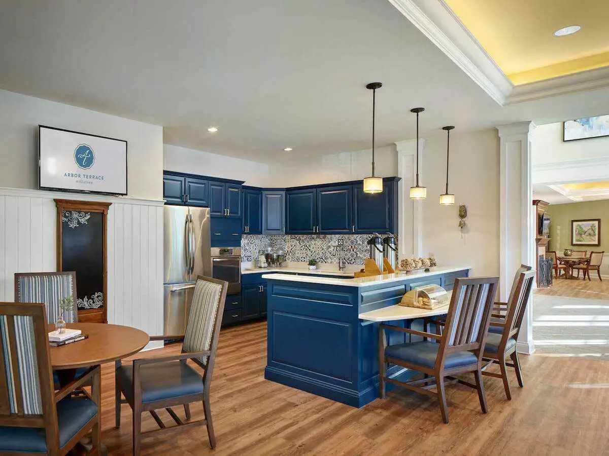 A kitchen with blue cabinets , a large island , a table and chairs.