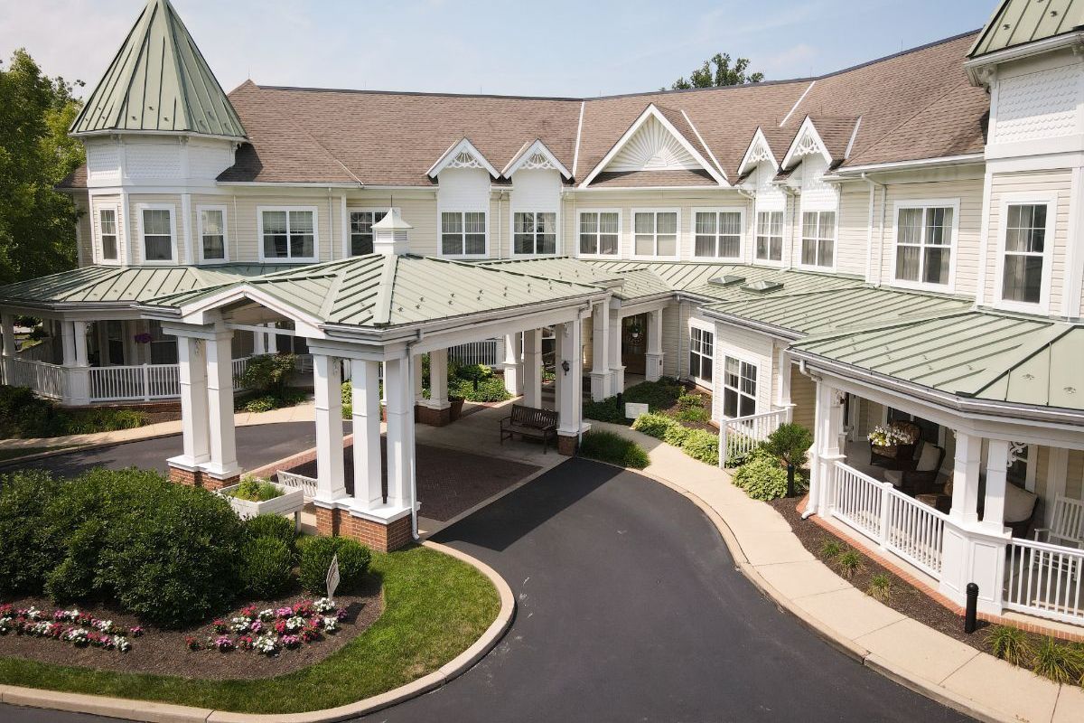An aerial view of a large white house with a green roof.