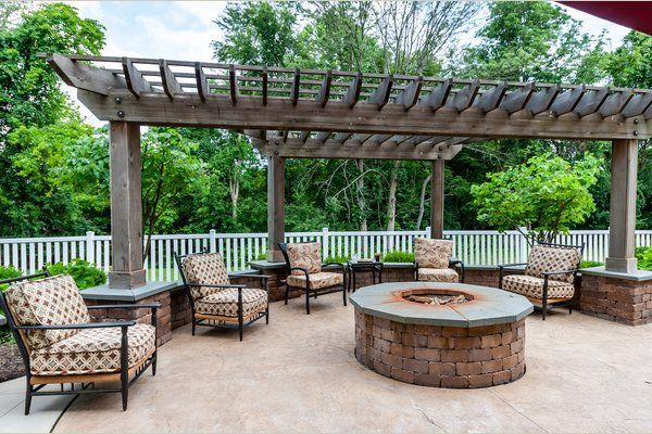 A patio with a fire pit and chairs under a pergola