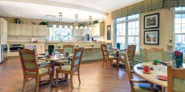 A dining room with tables and chairs and a kitchen in the background