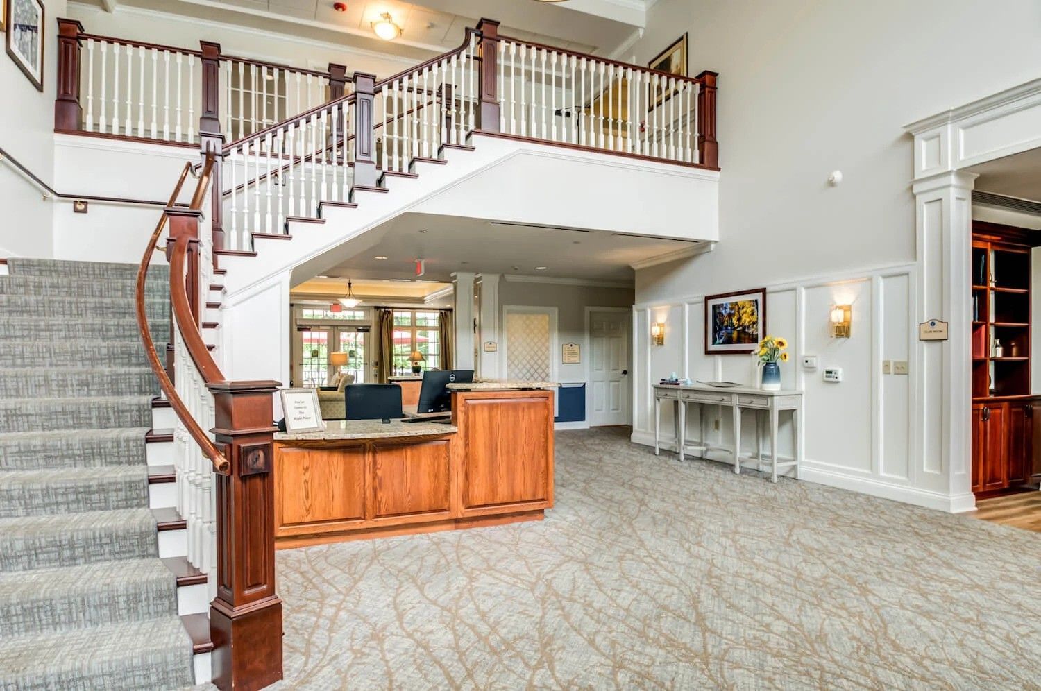 A large lobby with stairs leading up to the second floor and a reception desk.