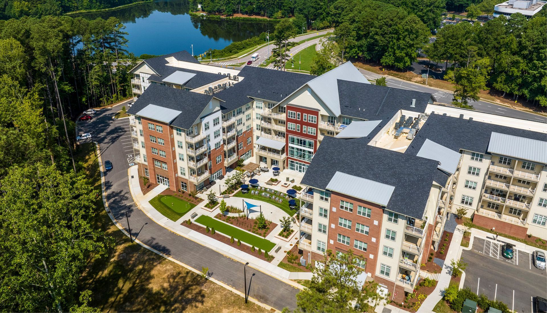 An aerial view of a large apartment building with a lake in the background.
