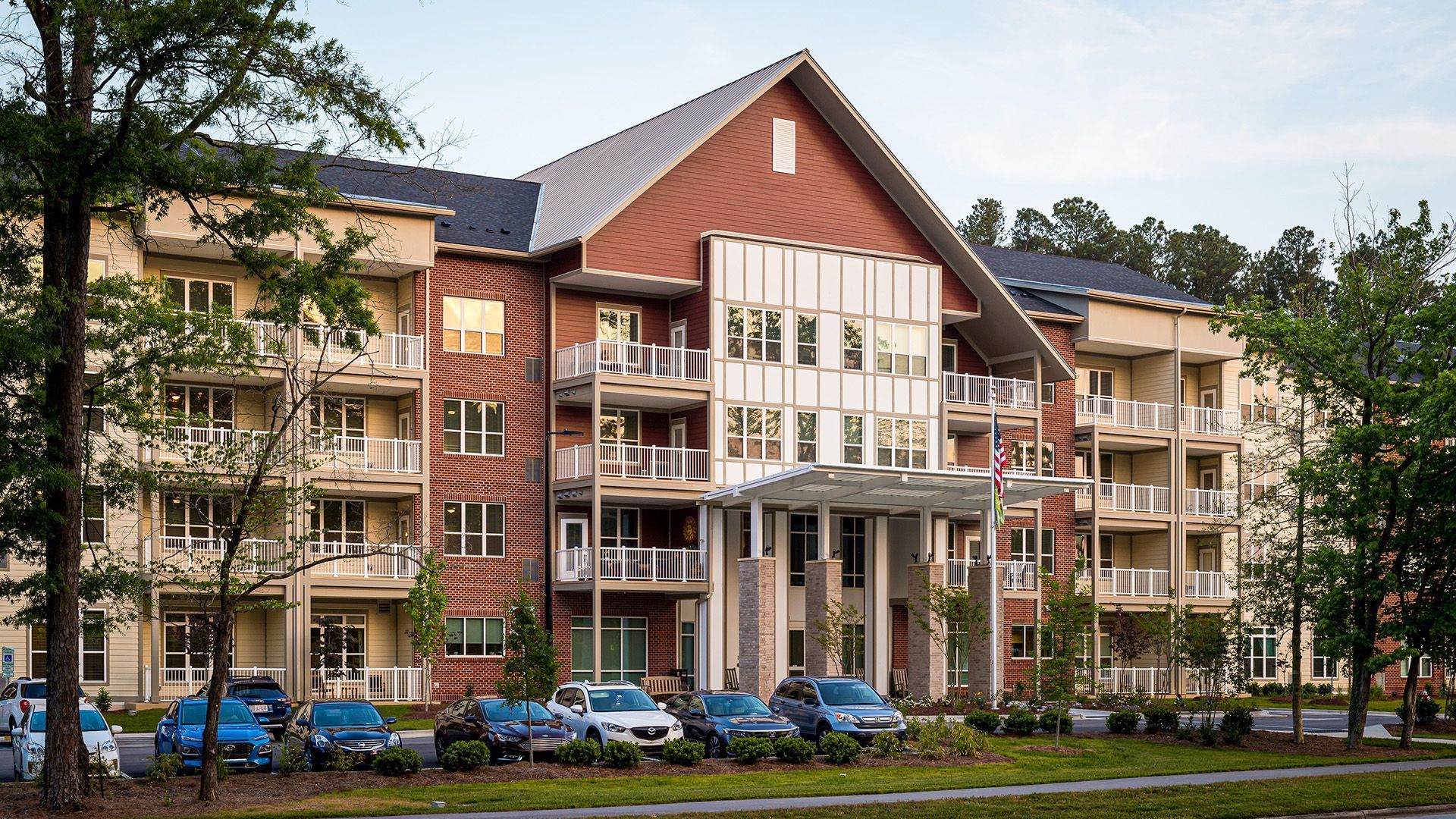 A large apartment building with cars parked in front of it.