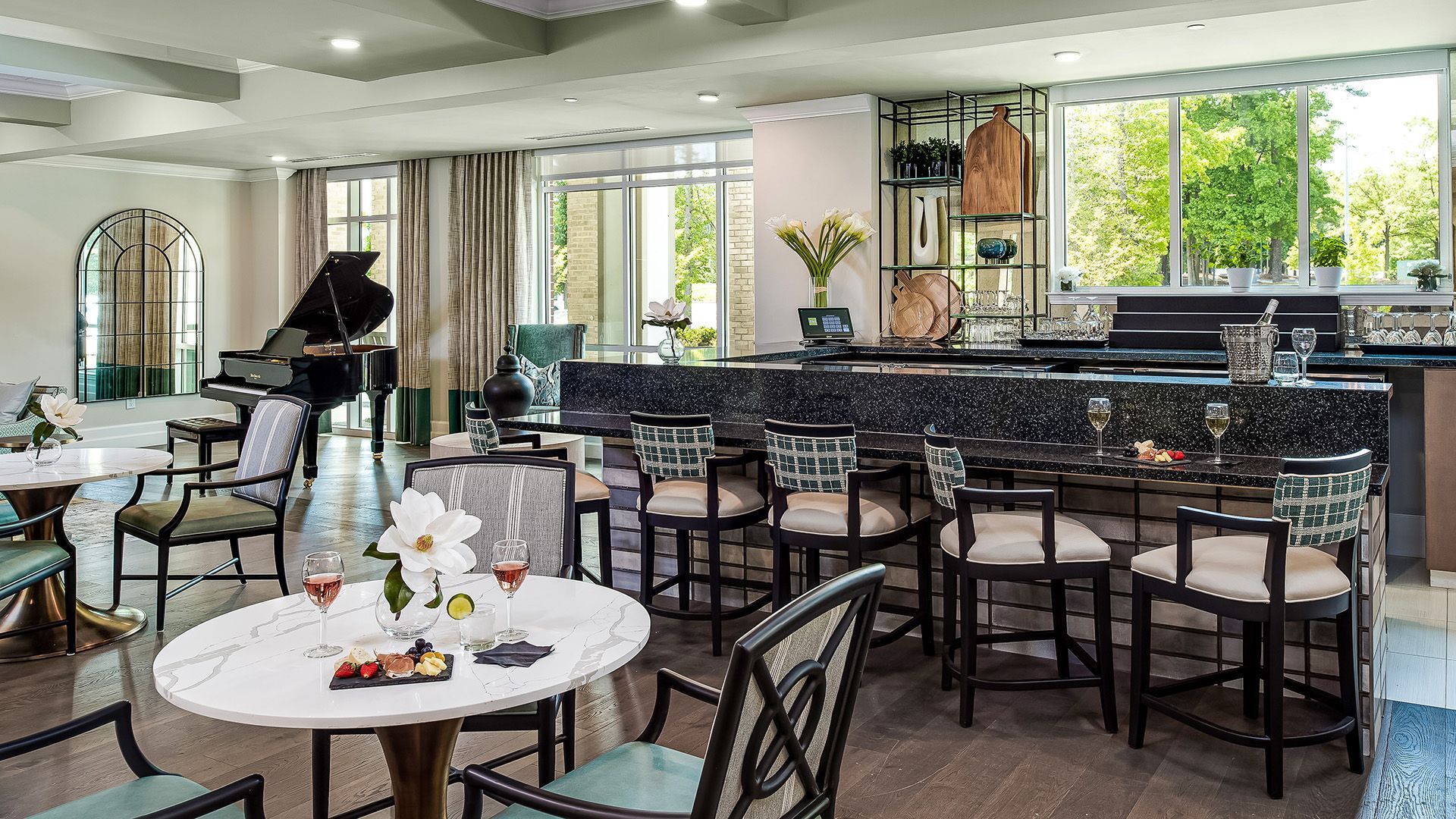 A large room with tables and chairs and a piano.