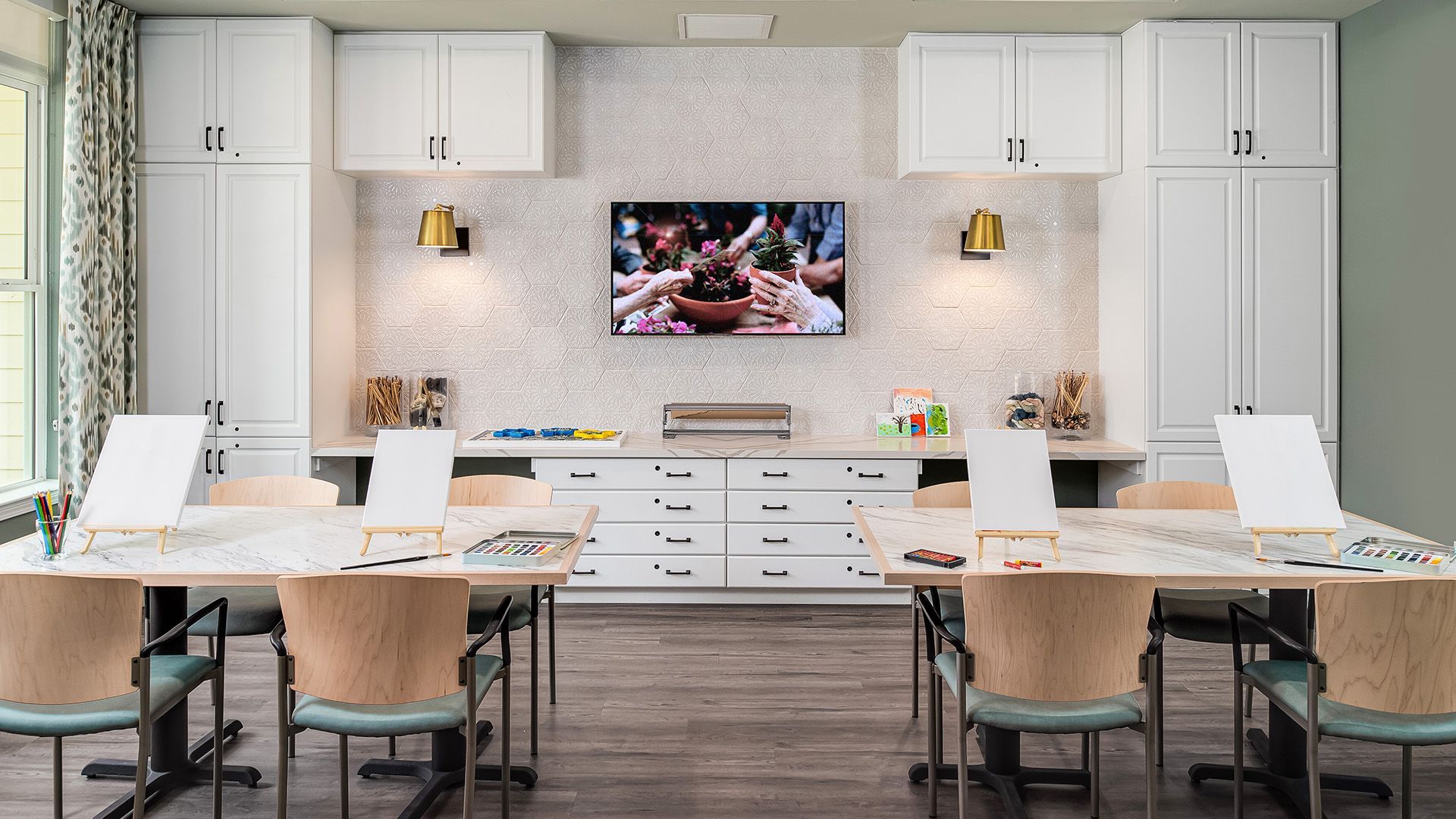 A room with tables and chairs and a television on the wall.
