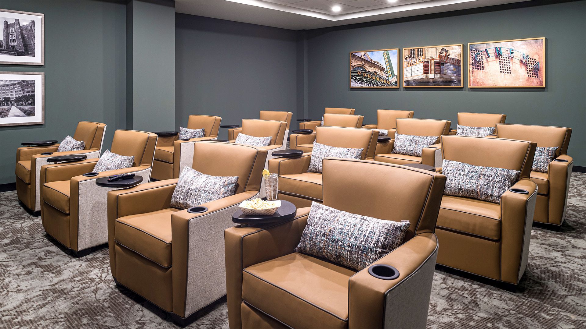 A row of brown leather chairs in a theater with pictures on the wall.