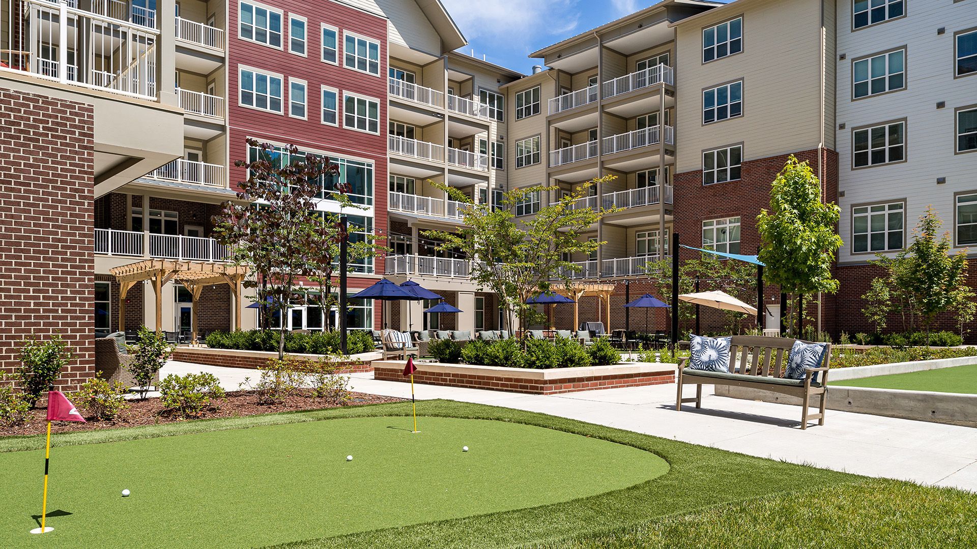 A putting green in front of a large apartment building.