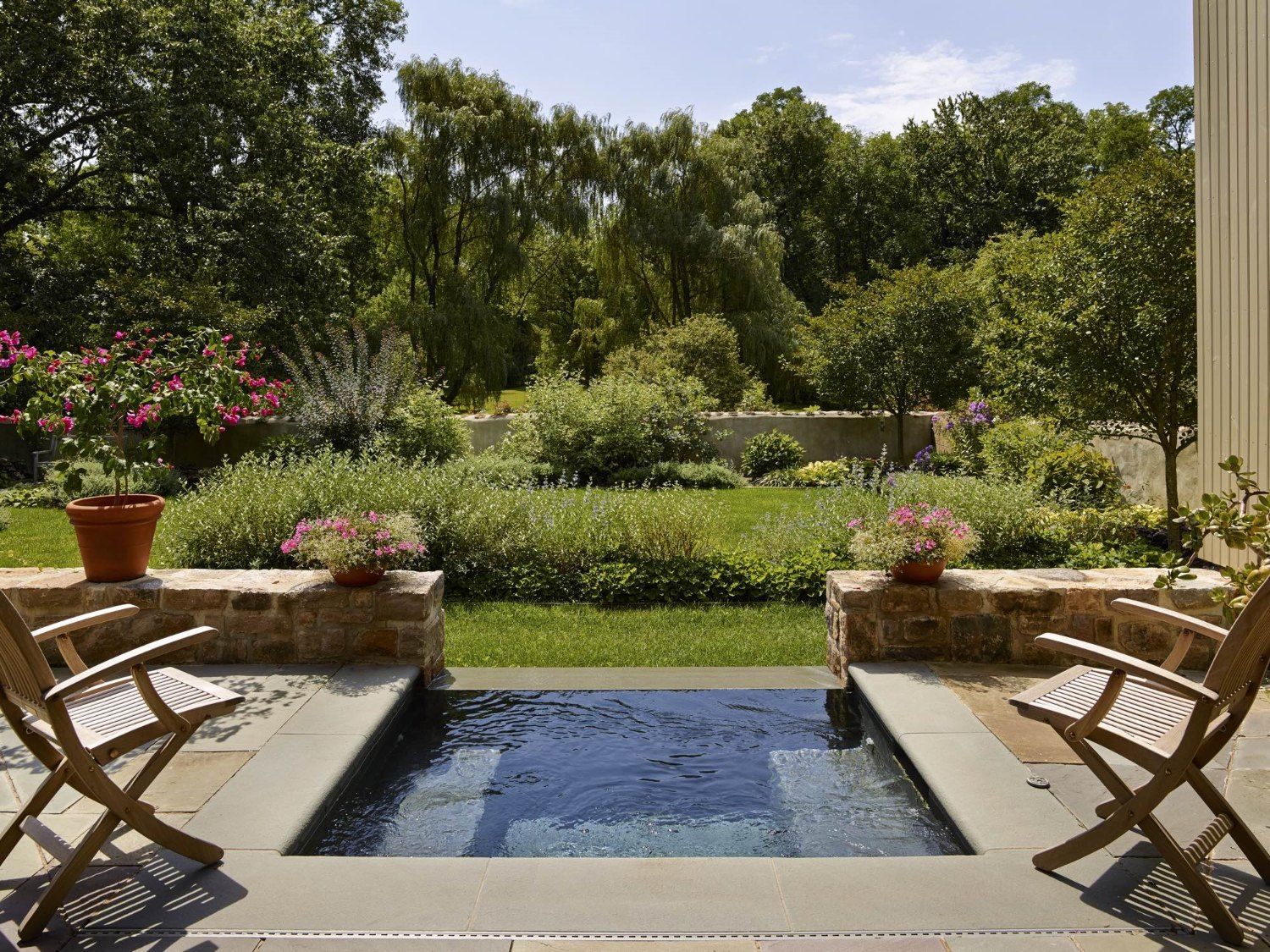 Two chairs are sitting next to a pool in a backyard