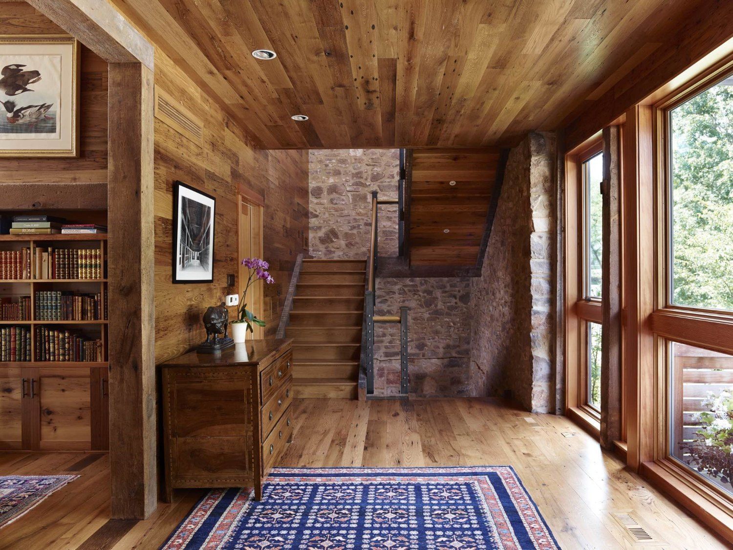 A wooden hallway with a rug and stairs