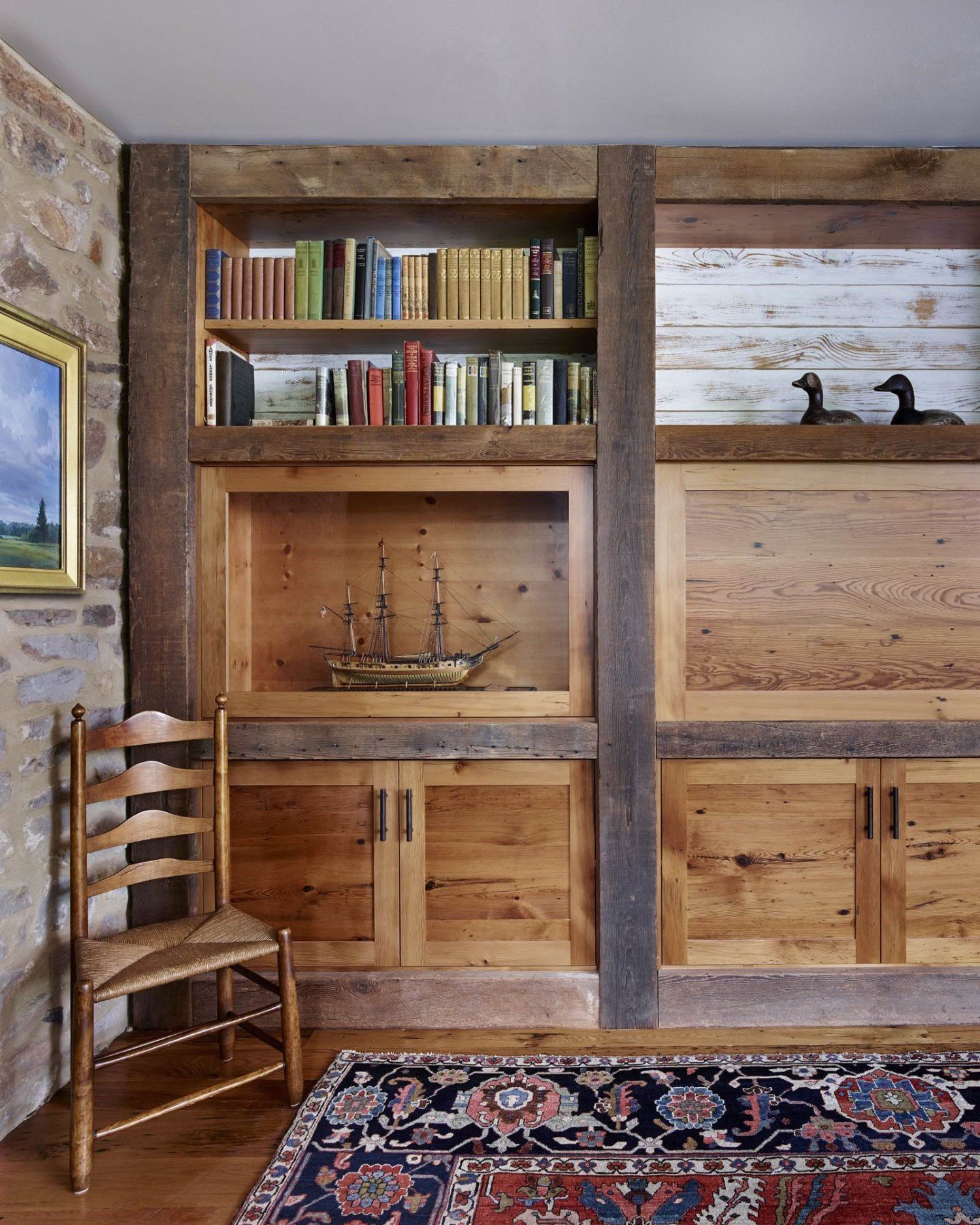 A living room with wooden cabinets , a chair and a rug.