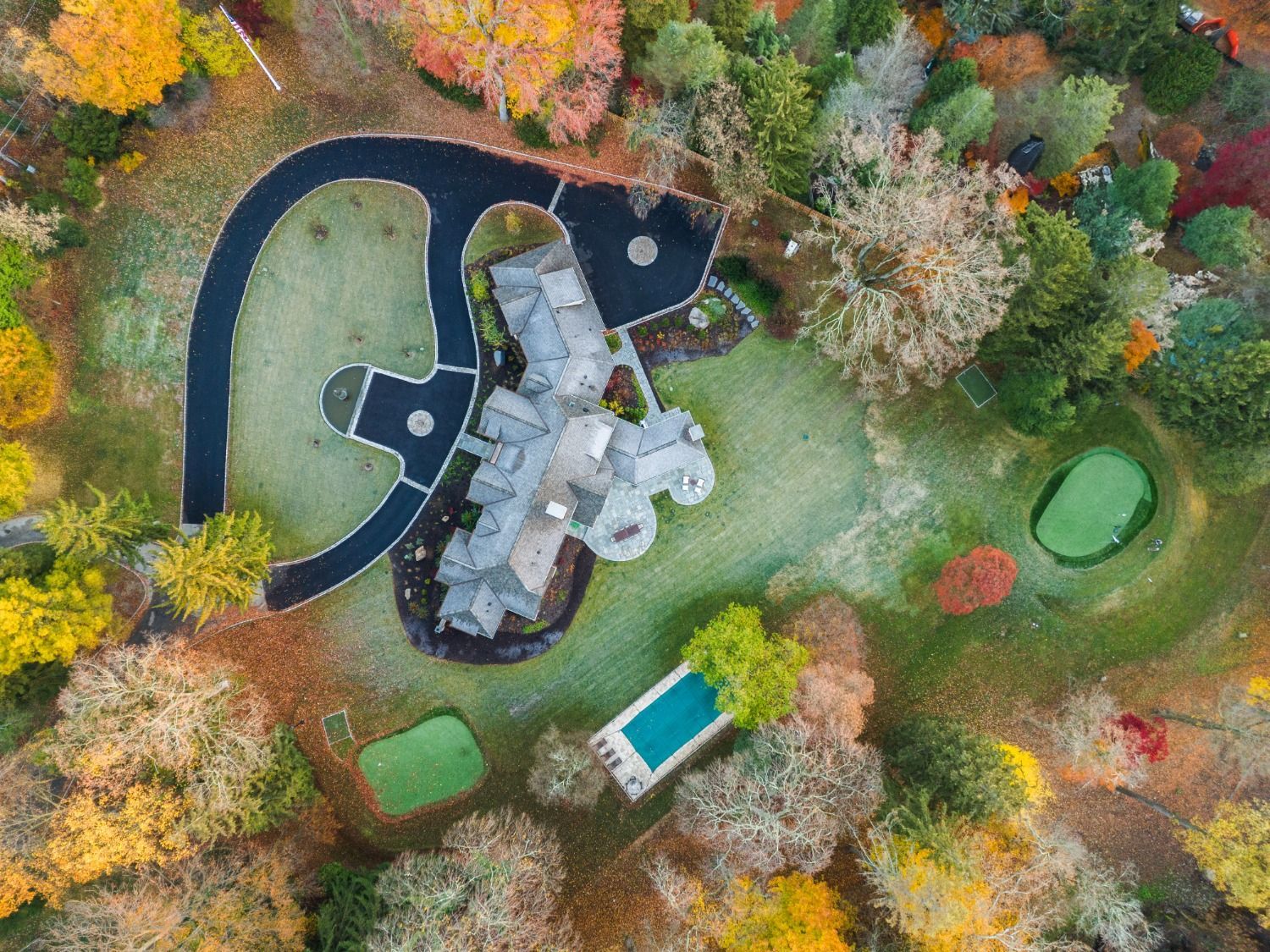 An aerial view of a house surrounded by trees and a pool.