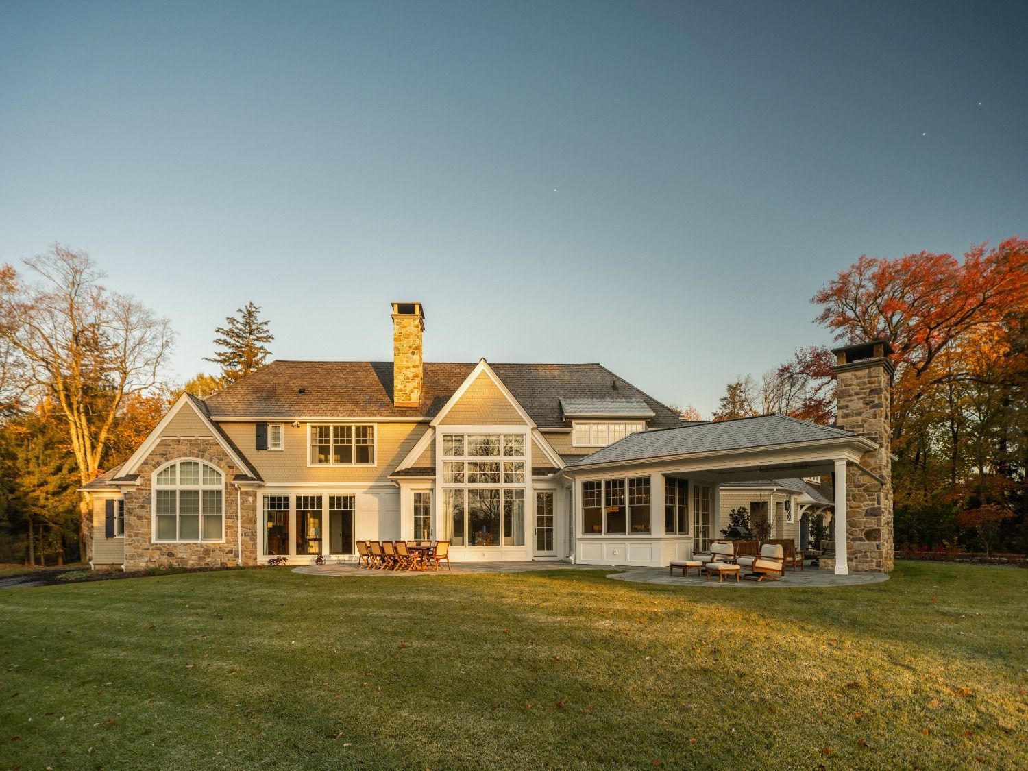 The back of a large house with a large lawn in front of it.