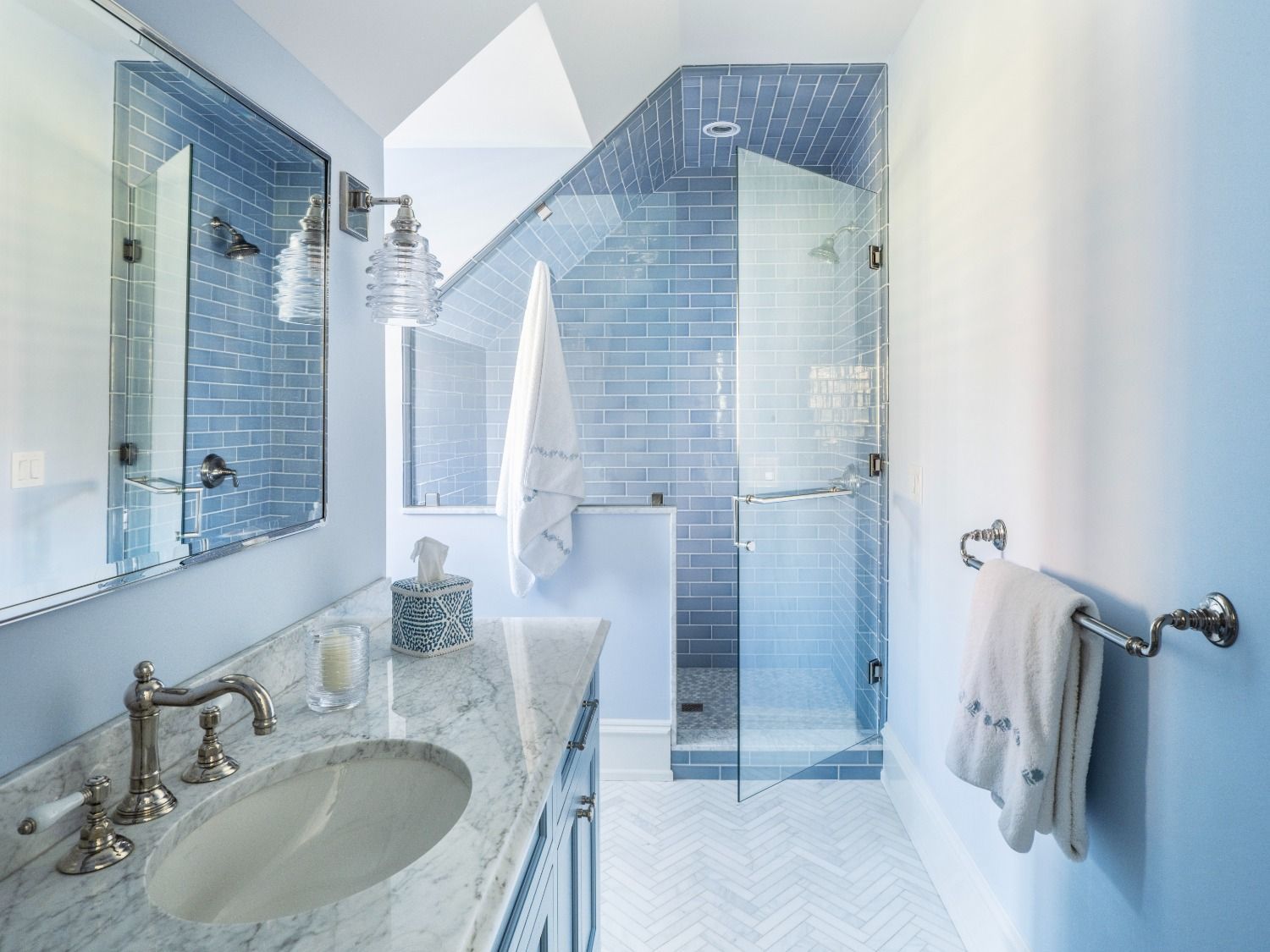 A bathroom with a sink , mirror , and walk in shower.