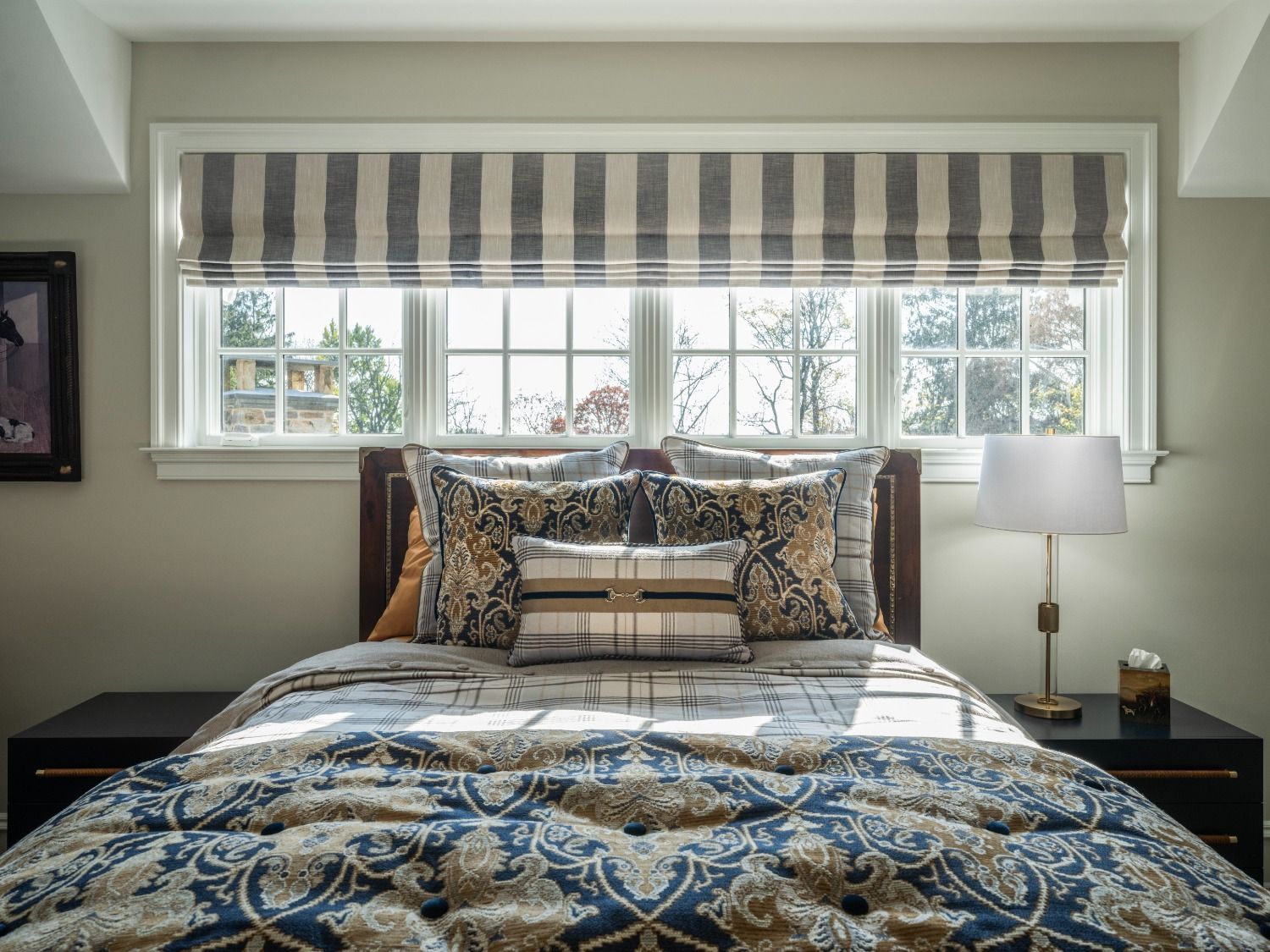 A bedroom with a bed , nightstand , lamp and window.
