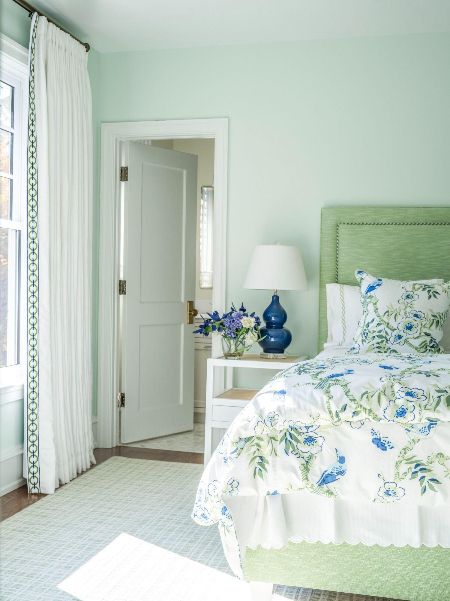 A bedroom with a bed , nightstand , lamp and window
