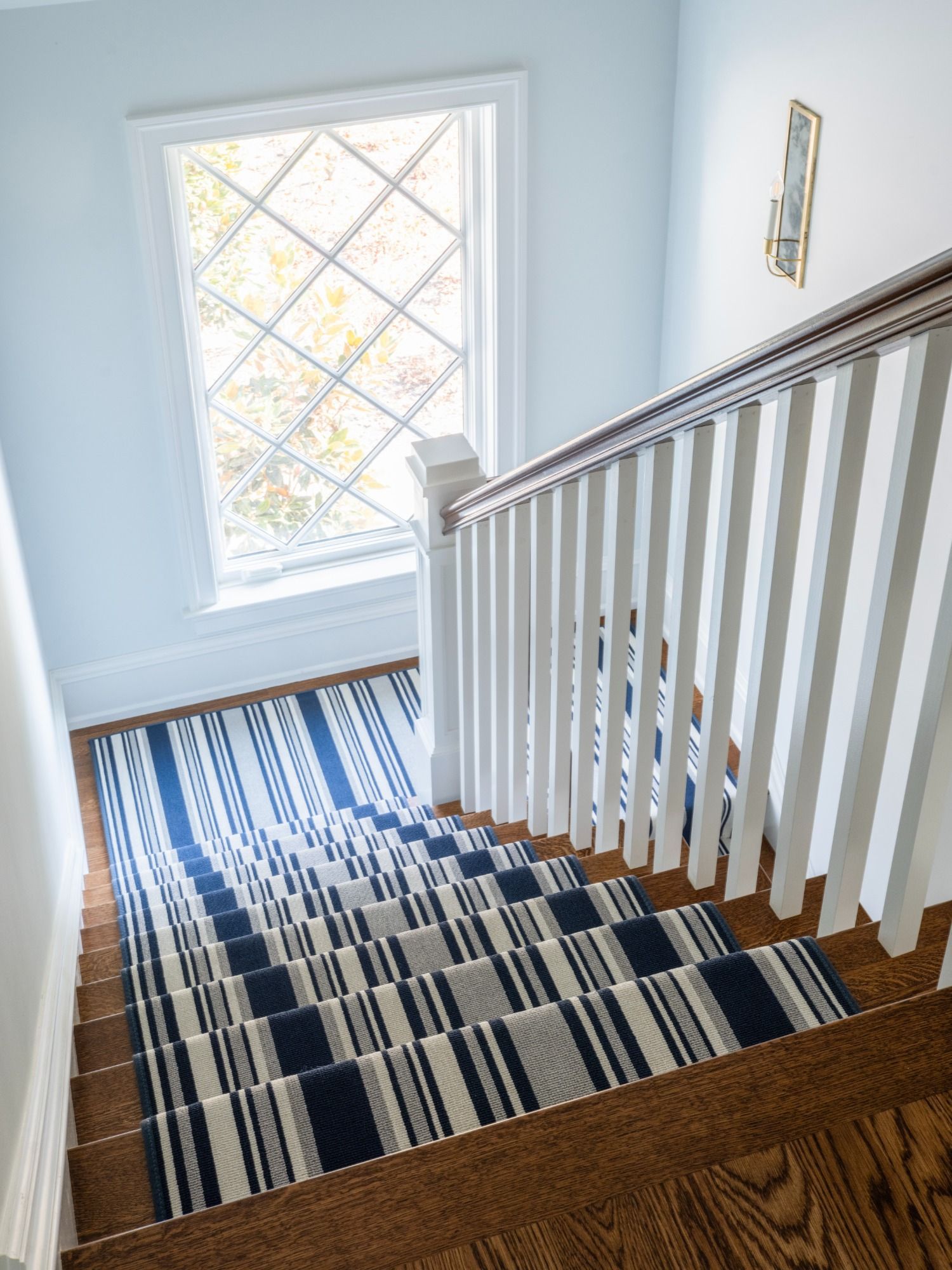 A staircase with a blue and white striped rug on the steps.