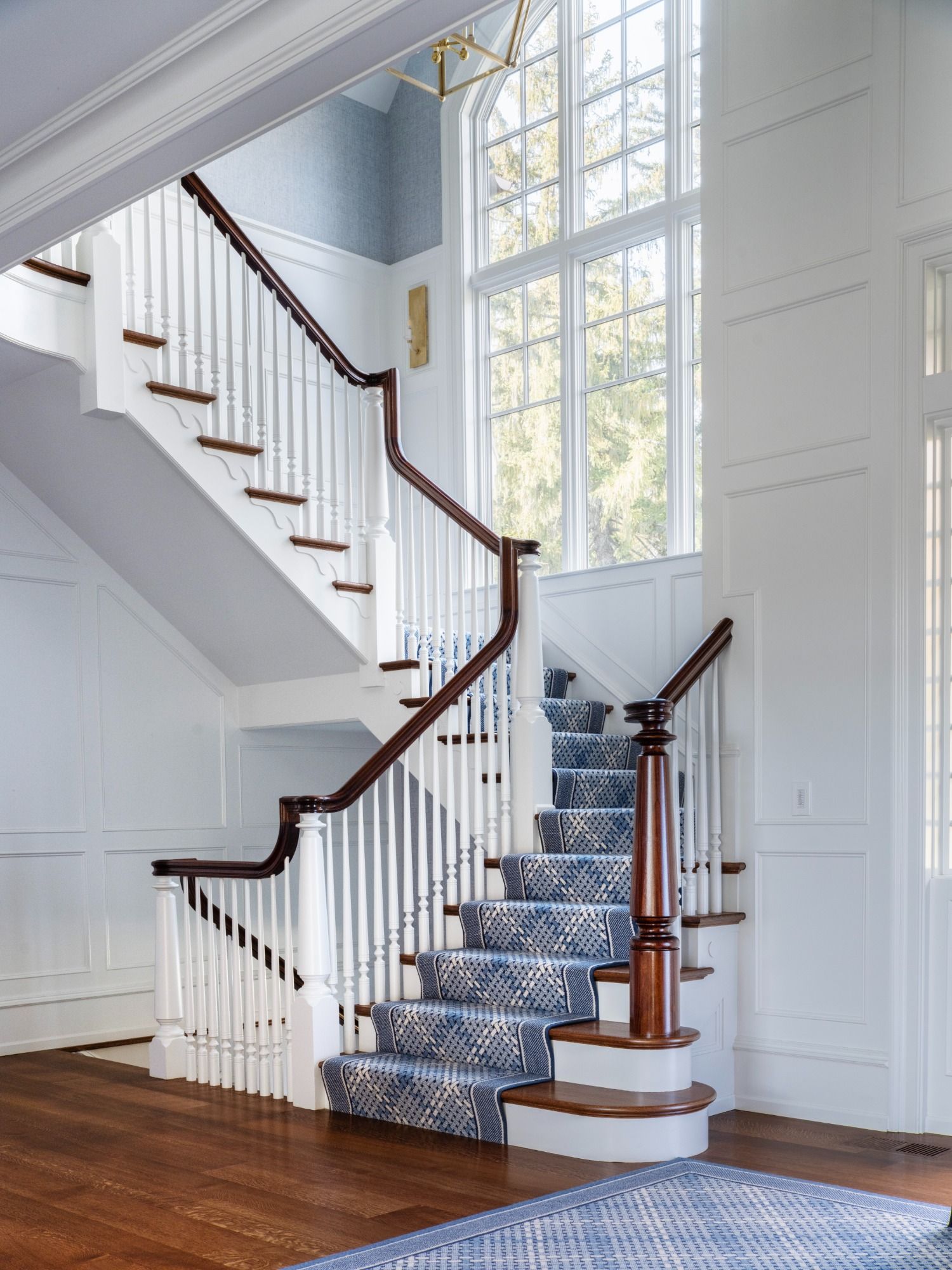 A staircase with a blue rug on the steps and a large window.