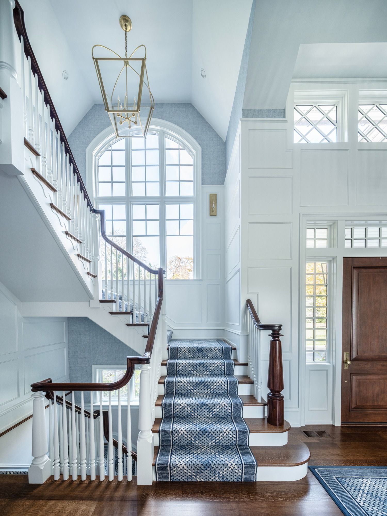 A staircase in a house with a blue carpet and a large window.