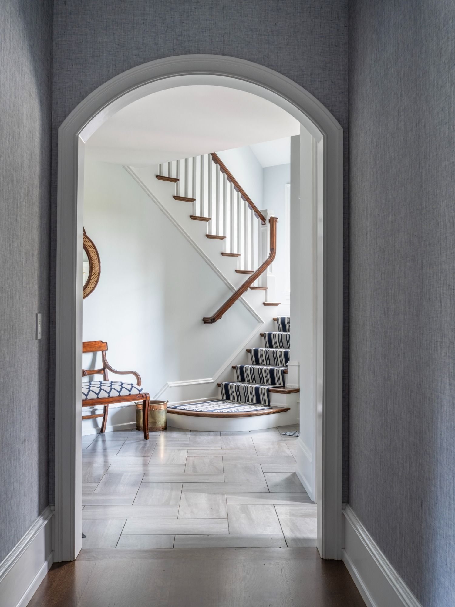 A hallway with a staircase and a chair in the background