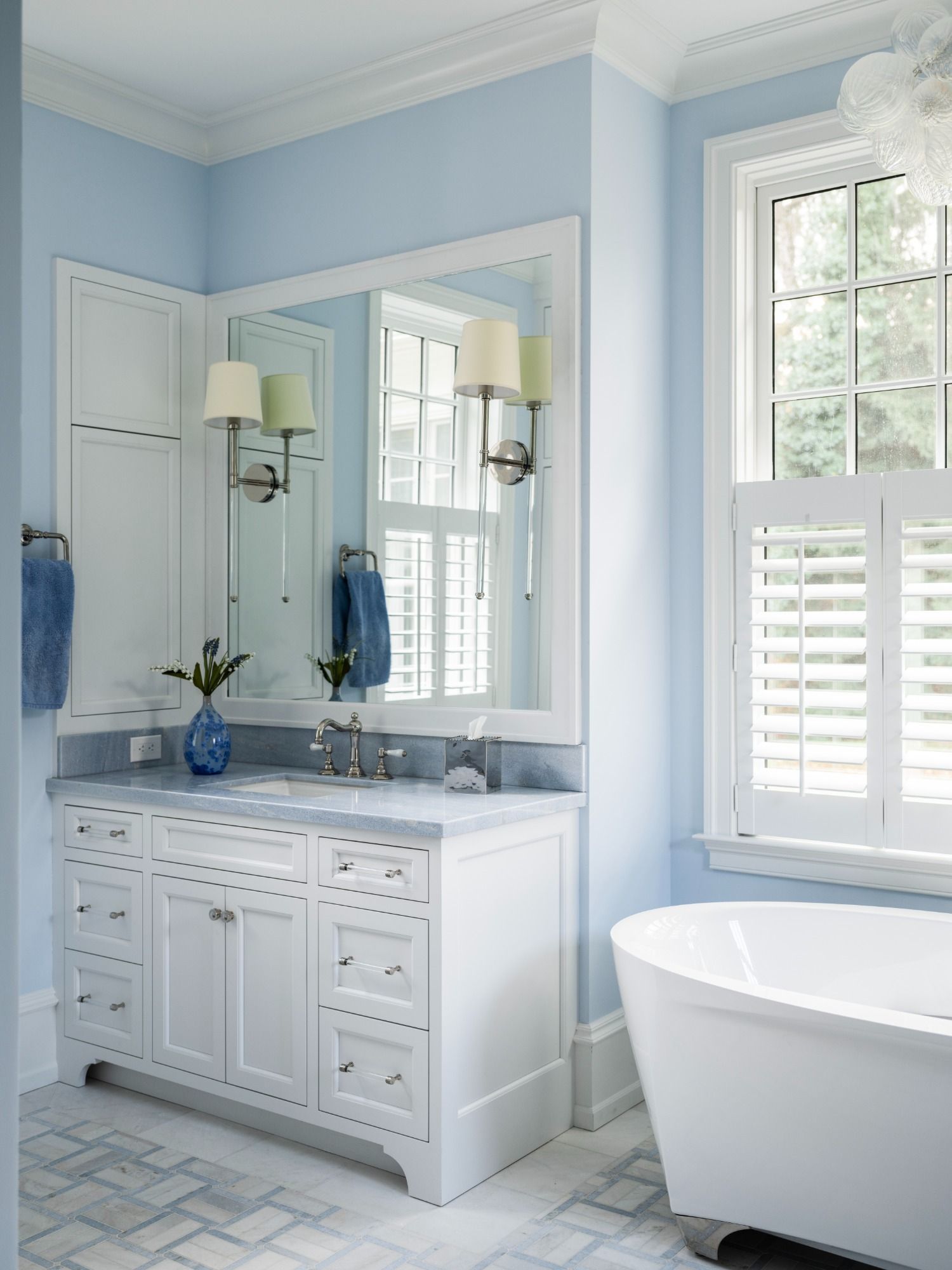A bathroom with blue walls and white cabinets and a tub