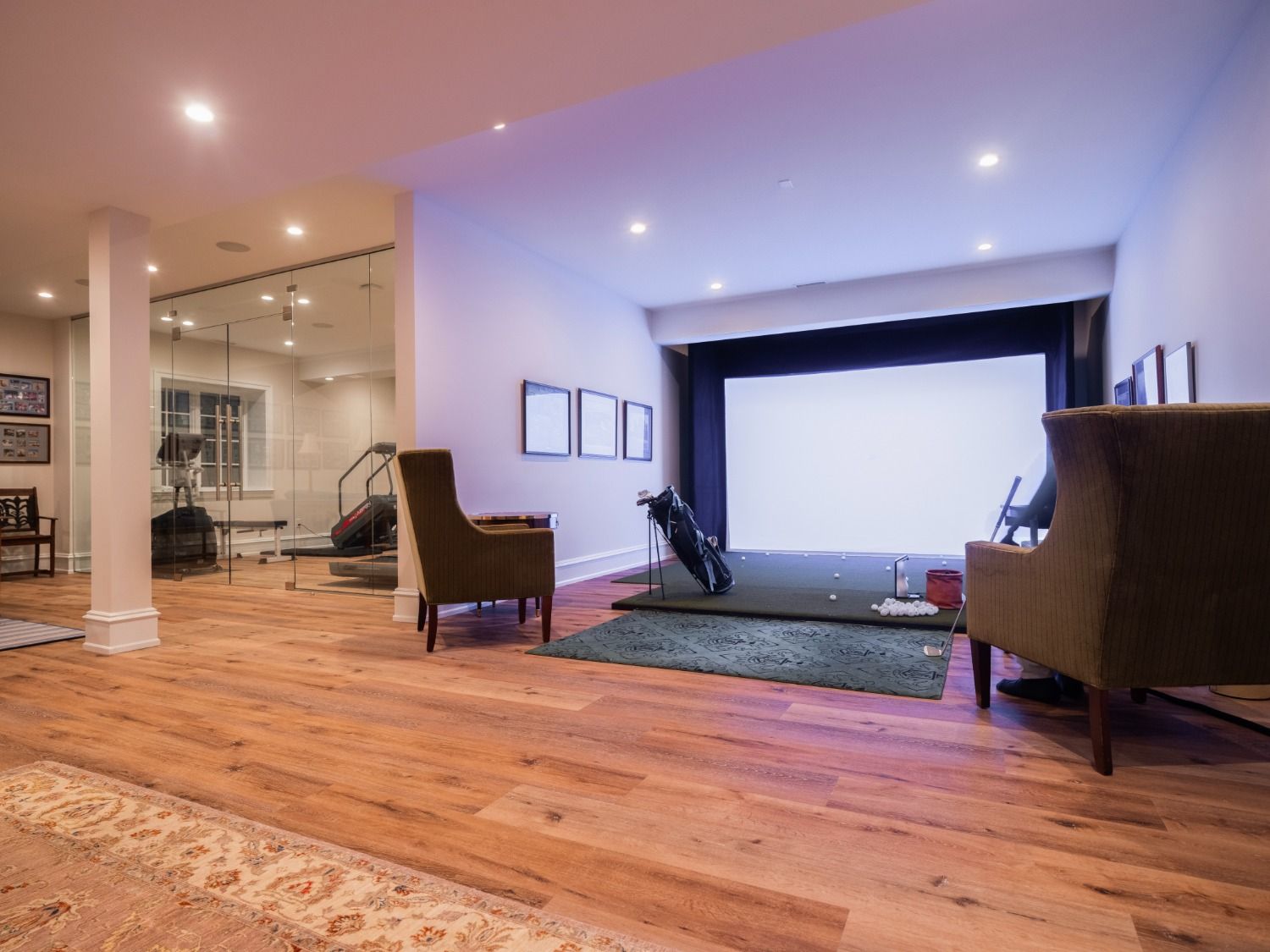 A living room with hardwood floors and a golf simulator.