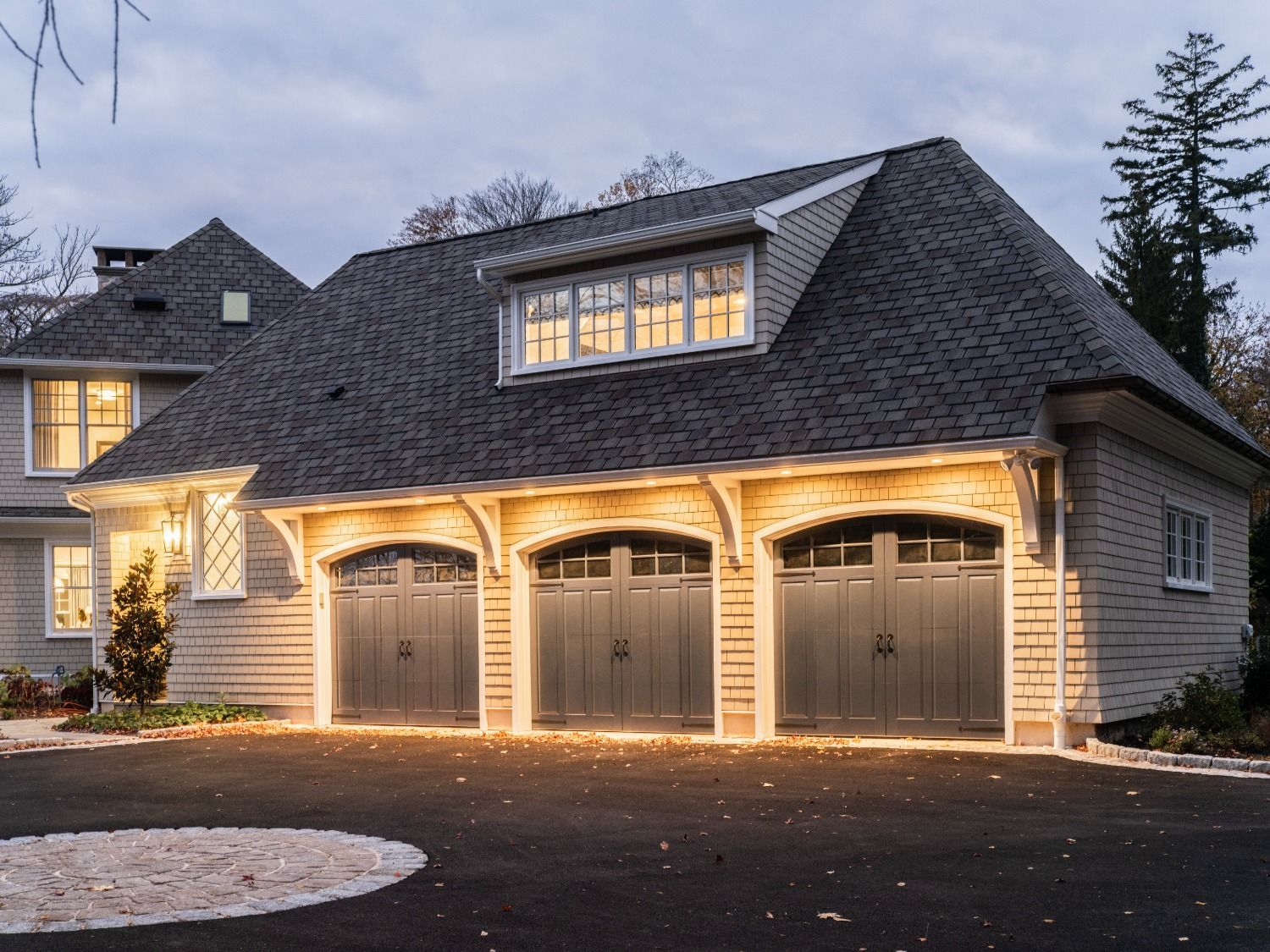 A house with three garage doors is lit up at night
