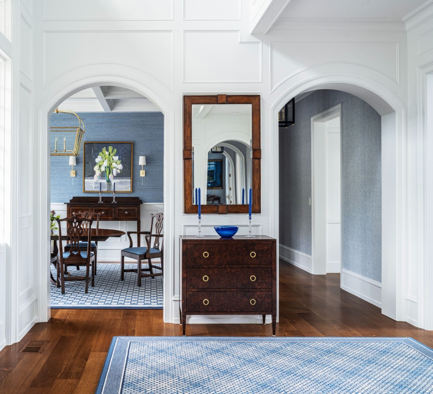 A hallway with a dresser and a mirror leading to a dining room.